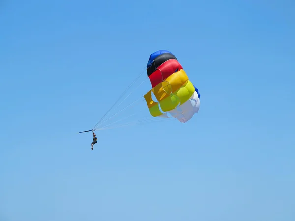 Fallschirmspringer auf buntem Fallschirm und blauem Himmel — Stockfoto
