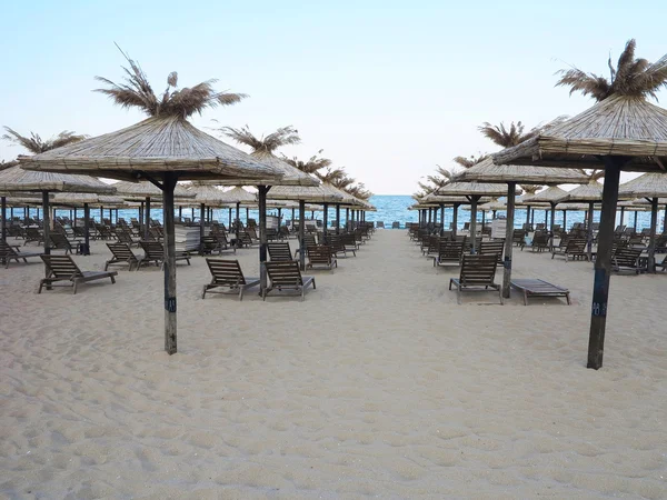 Liegestühle und Sonnenschirm im Sand am Meer, blauer Himmel — Stockfoto