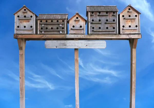 Old wooden starling nesting boxes bird house over blue sky Stock Photo