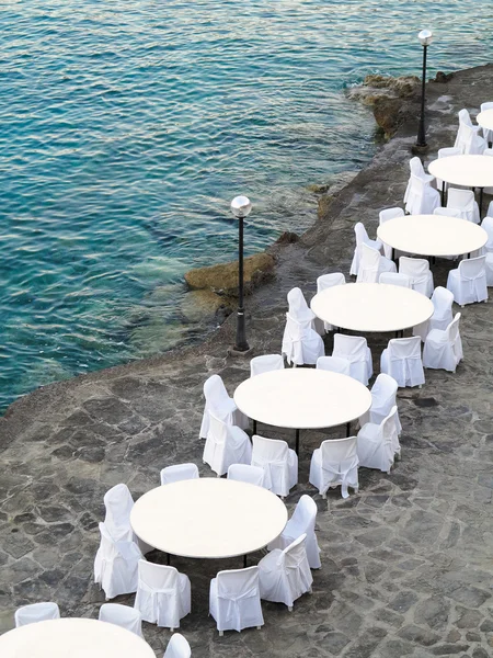 Restaurante ao ar livre perto do mar, cadeiras brancas e mesas — Fotografia de Stock