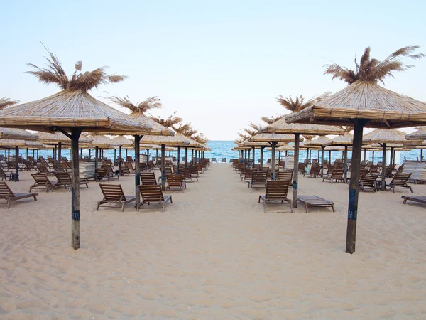 Пляжные шезлонги и зонтики на песке у моря, голубое небо — стоковое фото