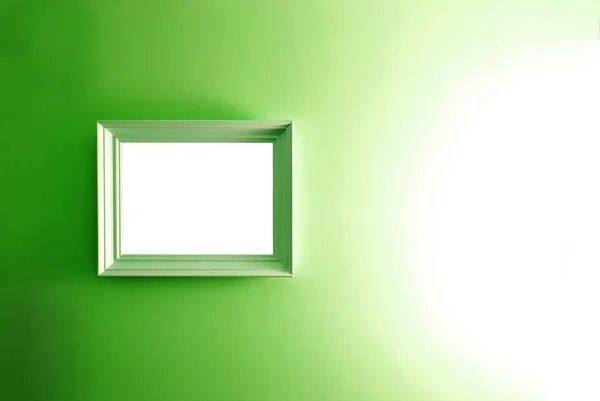 Bílý prázdný rámeček na zelené zdi. — Stock fotografie