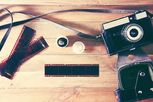 Retro vintage camera and photographic film on wooden background — Stock Photo, Image