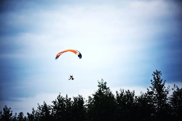 Motorized hang glider on the blue sky.