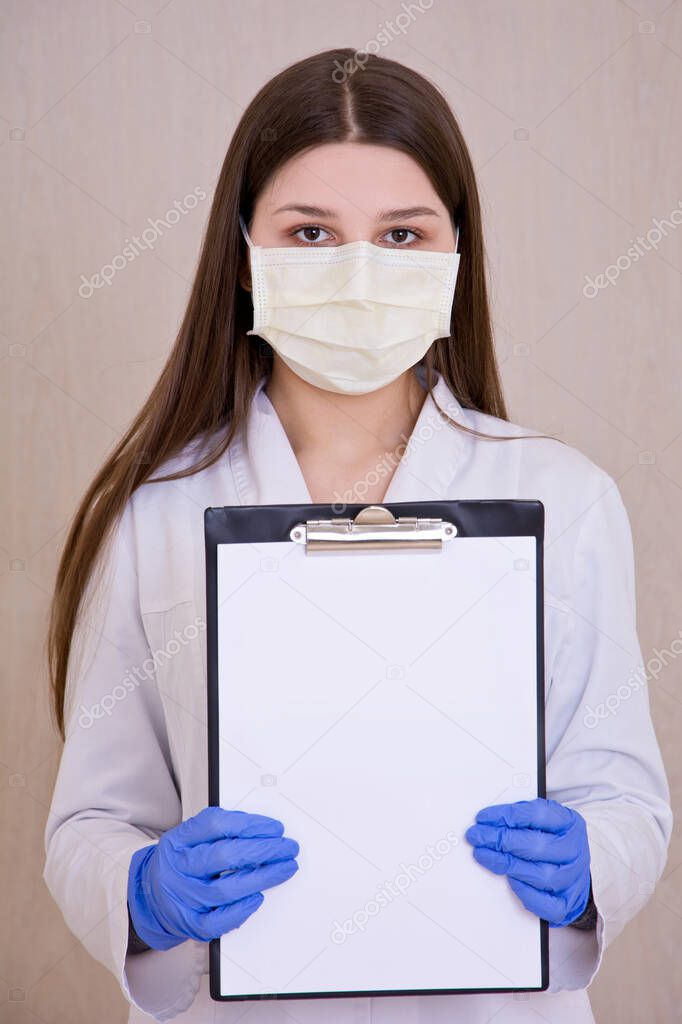 Female doctor wearing protection face mask holding notes. Free copy space. Covid-19 concept.