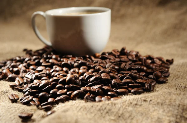 Κόκκους καφέ με κούπα σε ένα τραχύ απόλυση — Φωτογραφία Αρχείου