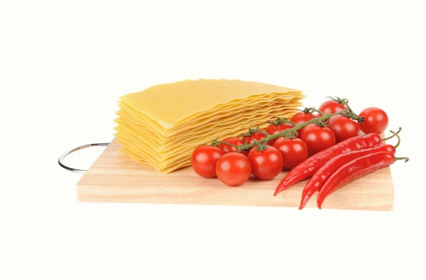 Pasta de lasaña y tomate y pimientos rojos en aislado de tabla de cortar —  Fotos de Stock