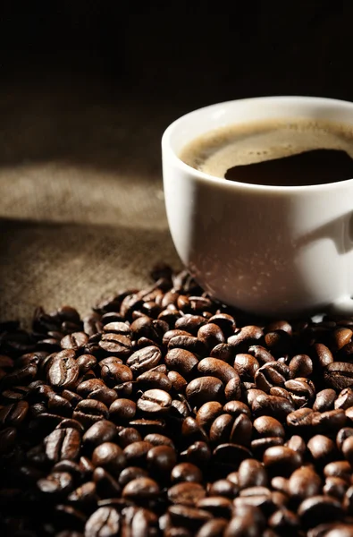 Granos de café con taza en un saqueo áspero — Foto de Stock