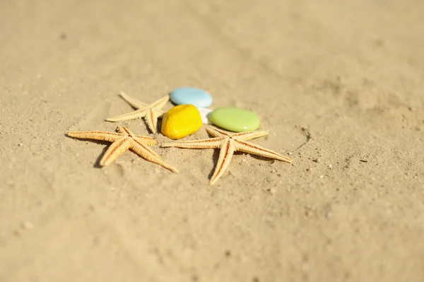 Starfish met kleurrijke kiezelsteen op zand — Stockfoto