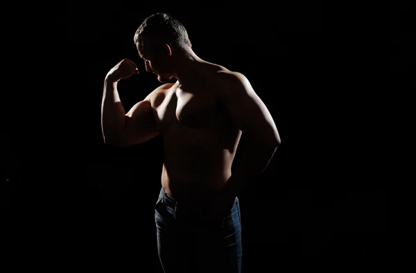 М'язистий чоловік позує на чорному тлі — стокове фото