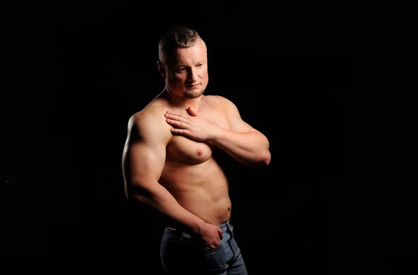 Muskulöser Mann posiert auf schwarzem Hintergrund — Stockfoto