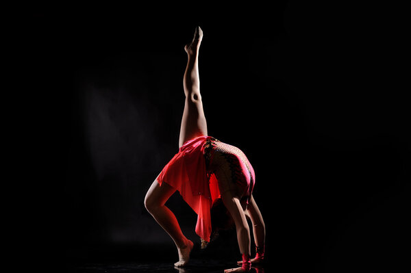 Young girl doing gymnastics on the black background