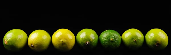 Grüne und gelbe Zitronen auf schwarzem Hintergrund — Stockfoto