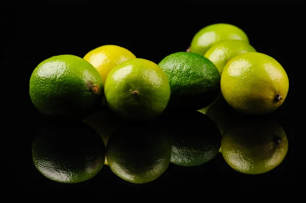 Grüne und gelbe Zitronen auf schwarzem Hintergrund — Stockfoto