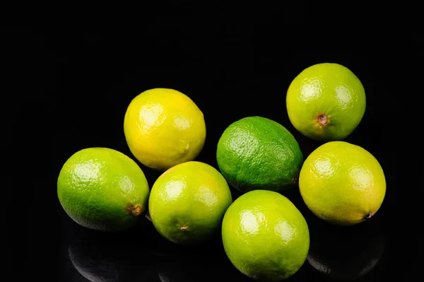 검은 배경에 있는 초록색과 노란색 레몬 — 스톡 사진