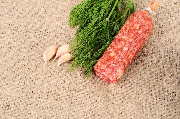 Чеснок укроп и колбаса на холсте — стоковое фото