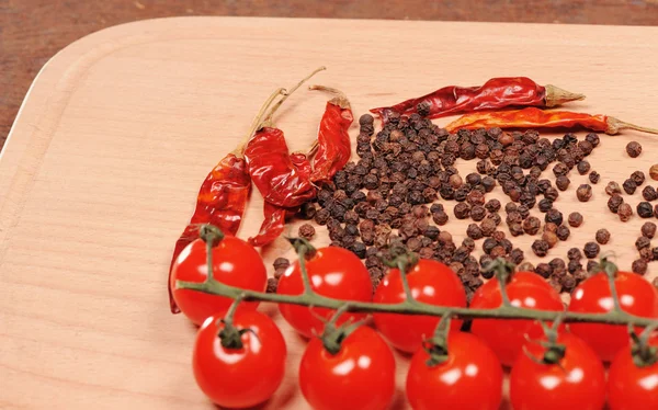 Poivre noir poivron rouge et tomate sur la planche à découper en bois — Photo