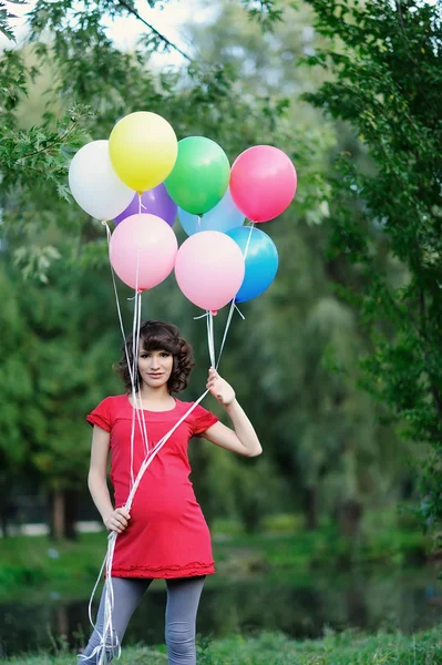 Счастливая беременная женщина с воздушными шарами в руках — стоковое фото