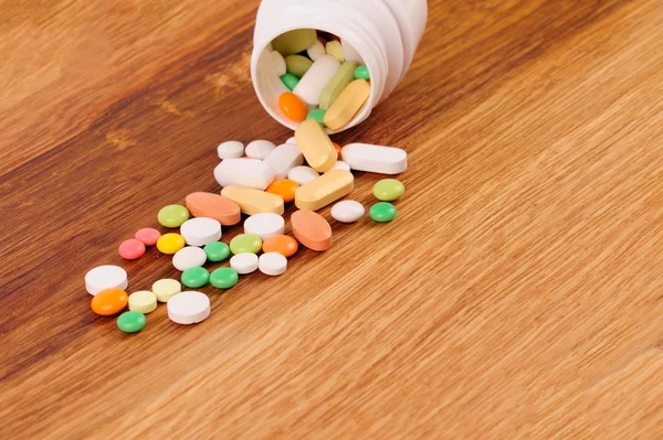 Altura de pílulas perto do recipiente aberto na mesa de madeira — Fotografia de Stock