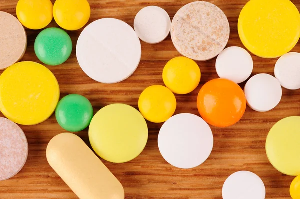 Heap of pills on wooden desk — Stock Photo, Image