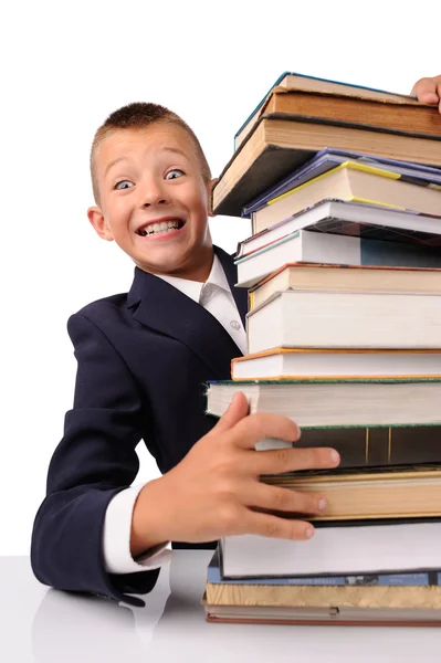 Förvånad skolpojke med enorma högen med böcker — Stockfoto