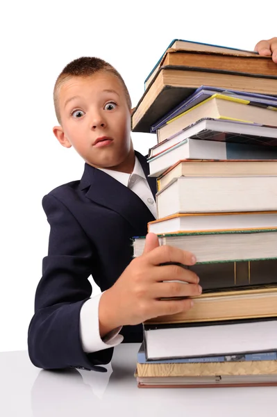 Verrast schooljongen met enorme stapel boeken — Stockfoto