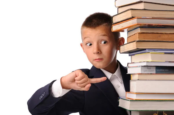 Schoolboy pointing to huge stack of books — Stock Photo, Image