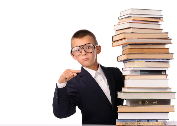 Schoolboy apontando para enorme pilha de livros — Fotografia de Stock