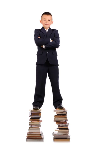 Schoolboy de pé sobre a enorme pilha de livros — Fotografia de Stock