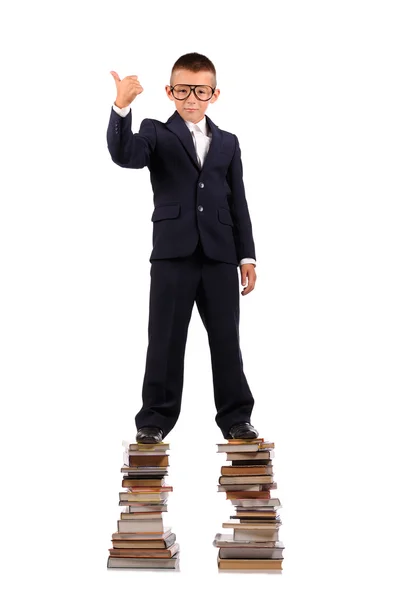 Школьник стоит на огромной стопке книг — стоковое фото