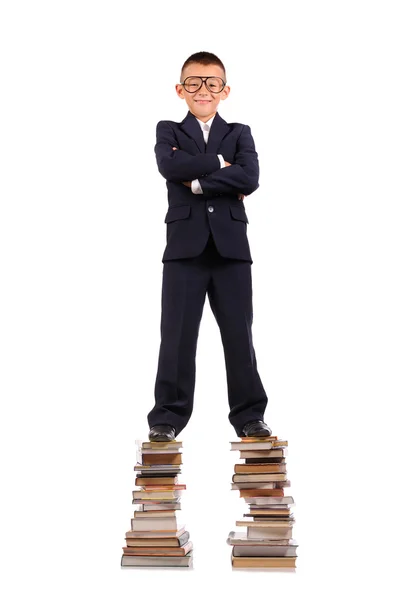 Schoolboy de pé sobre a enorme pilha de livros — Fotografia de Stock