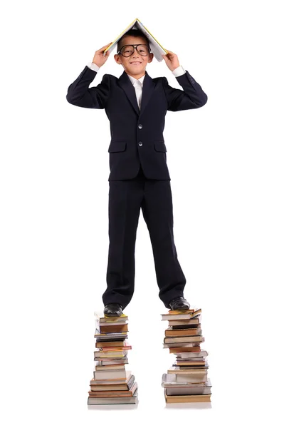 Schoolboy de pé sobre a enorme pilha de livros — Fotografia de Stock