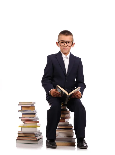 Schoolboy sentado na pilha enorme de livros — Fotografia de Stock
