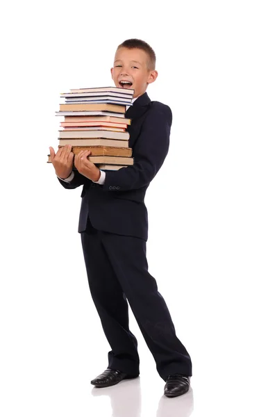 Schooljongen bedrijf enorme stapel boeken — Stockfoto