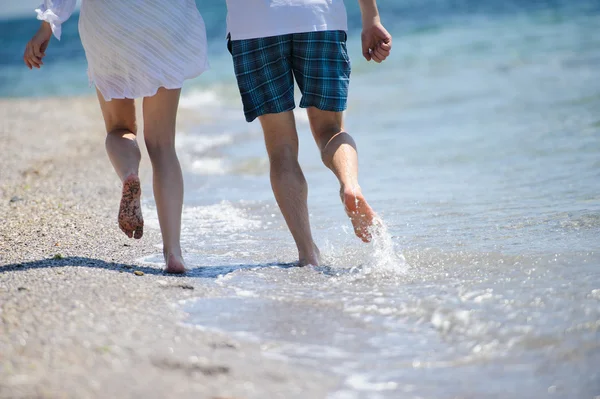 Feliz casal correndo na praia do mar Fotografia De Stock