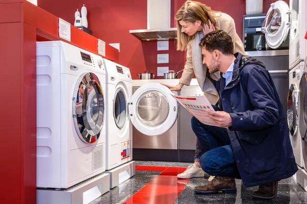 Casal escolhendo máquina de lavar no hipermercado — Fotografia de Stock