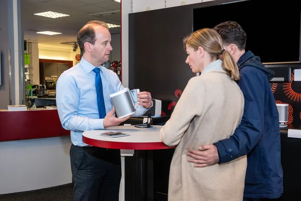 Vendedor mostrando altavoz compacto a la pareja en la tienda — Foto de Stock