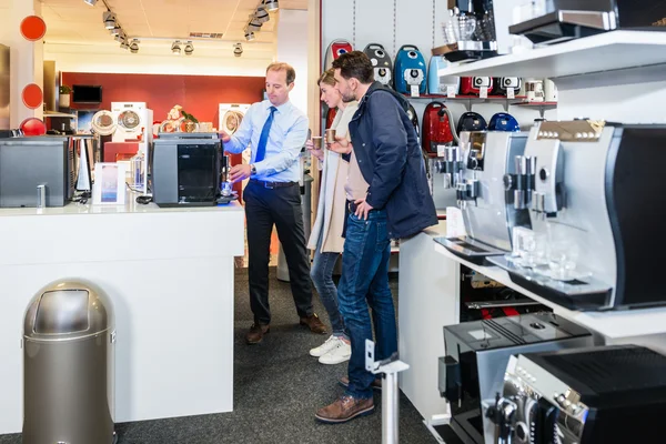 Salesman dimostrando caffettiera per coppia in negozio — Foto Stock