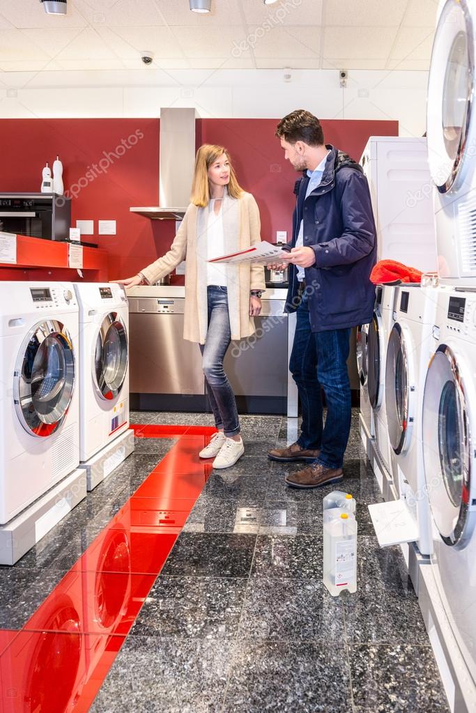 Couple Choosing Washing Machine In Hypermarket Stock Photo by