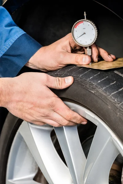 Mechaniker drückt Messgerät in Reifenprofil — Stockfoto