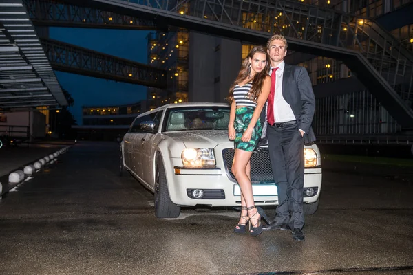 Pareja elegante de pie delante del coche — Foto de Stock