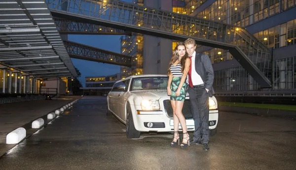 Cute couple in front of a limousine — Stock Photo, Image