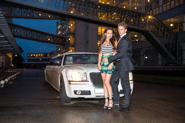 Elegant couple standing in front of limousine — Stock Photo, Image