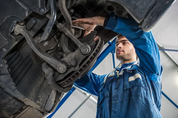 Male mechanic repairing suspension system — Stock Photo, Image