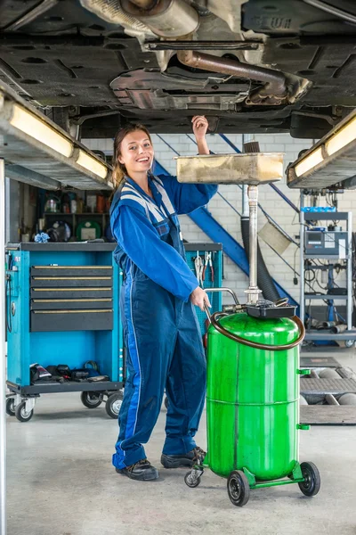 Kvinna reparera bilen på hydraulisk lyft — Stockfoto