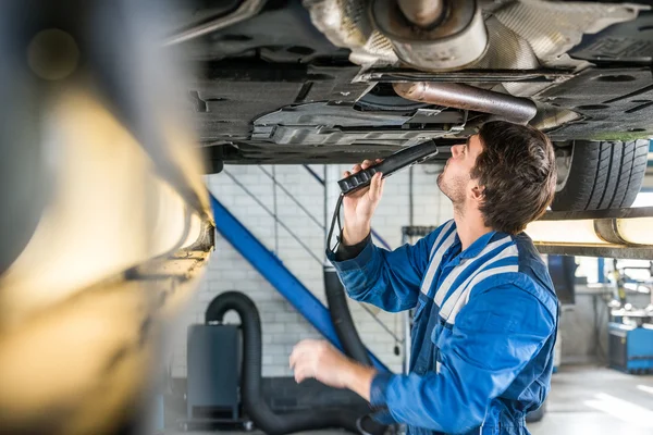 Mecánico masculino examinando debajo del coche —  Fotos de Stock