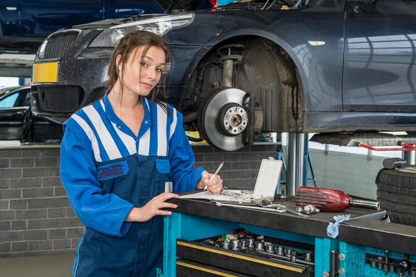 Kvinnlig mekaniker skriva noter nära bil — Stockfoto