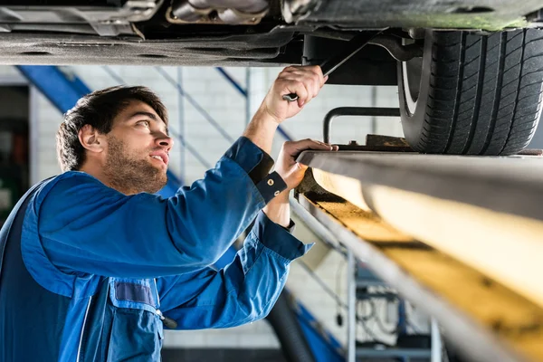 Manliga mekaniker som jobbade under bilen — Stockfoto