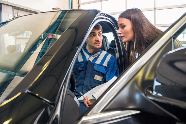 Mecánico sentado en el coche mientras explica al cliente —  Fotos de Stock