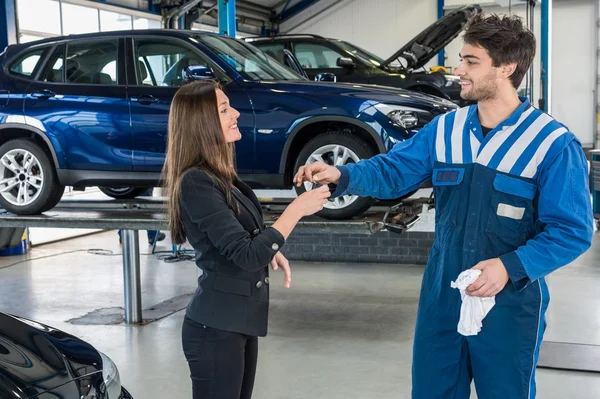 Geschäftsfrau erhält Autoschlüssel von Mechaniker — Stockfoto